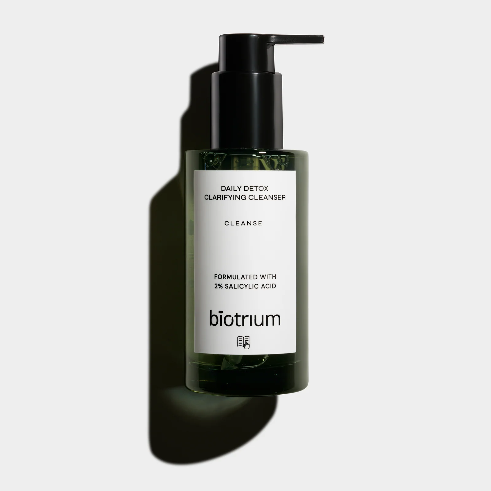 Front view of a green Biotrium Daily Detox cleanser bottle with a black pump and a defined shadow on a light background.