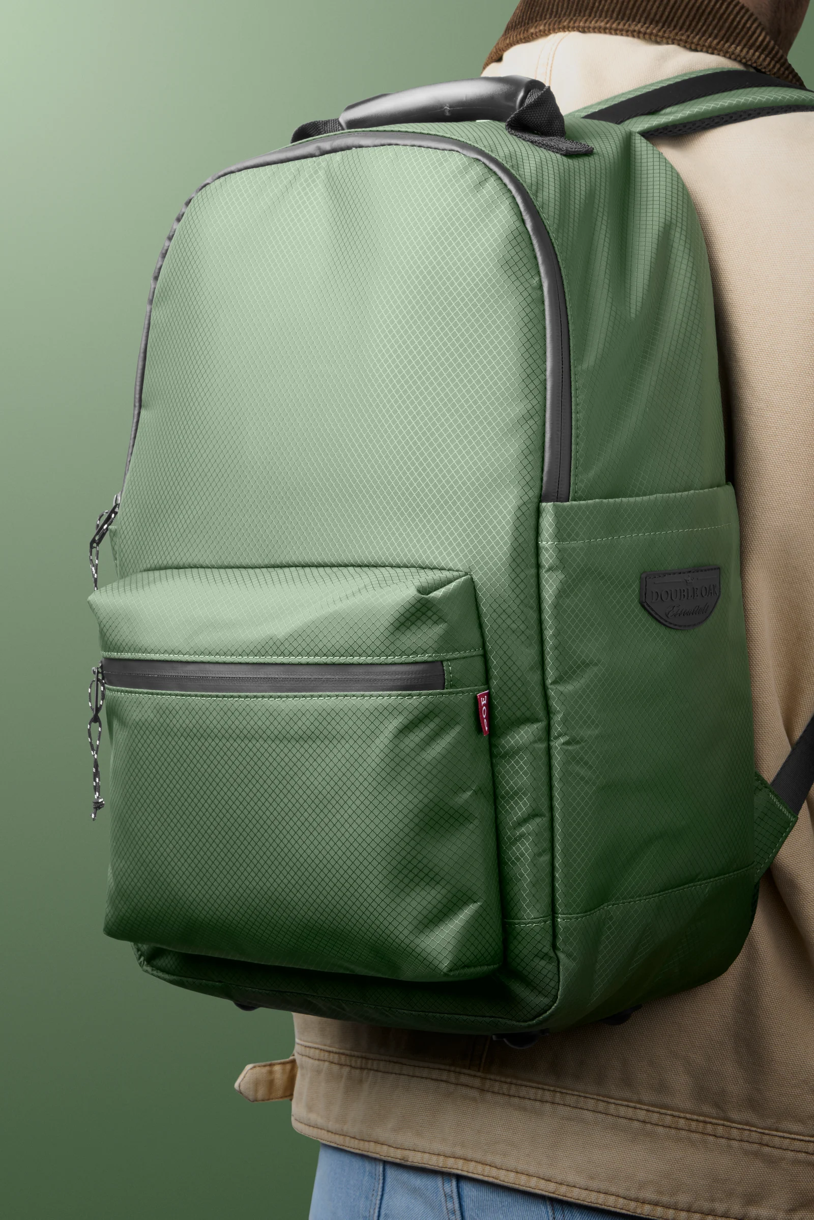 Person wearing a green Double Oak backpack against a green background.