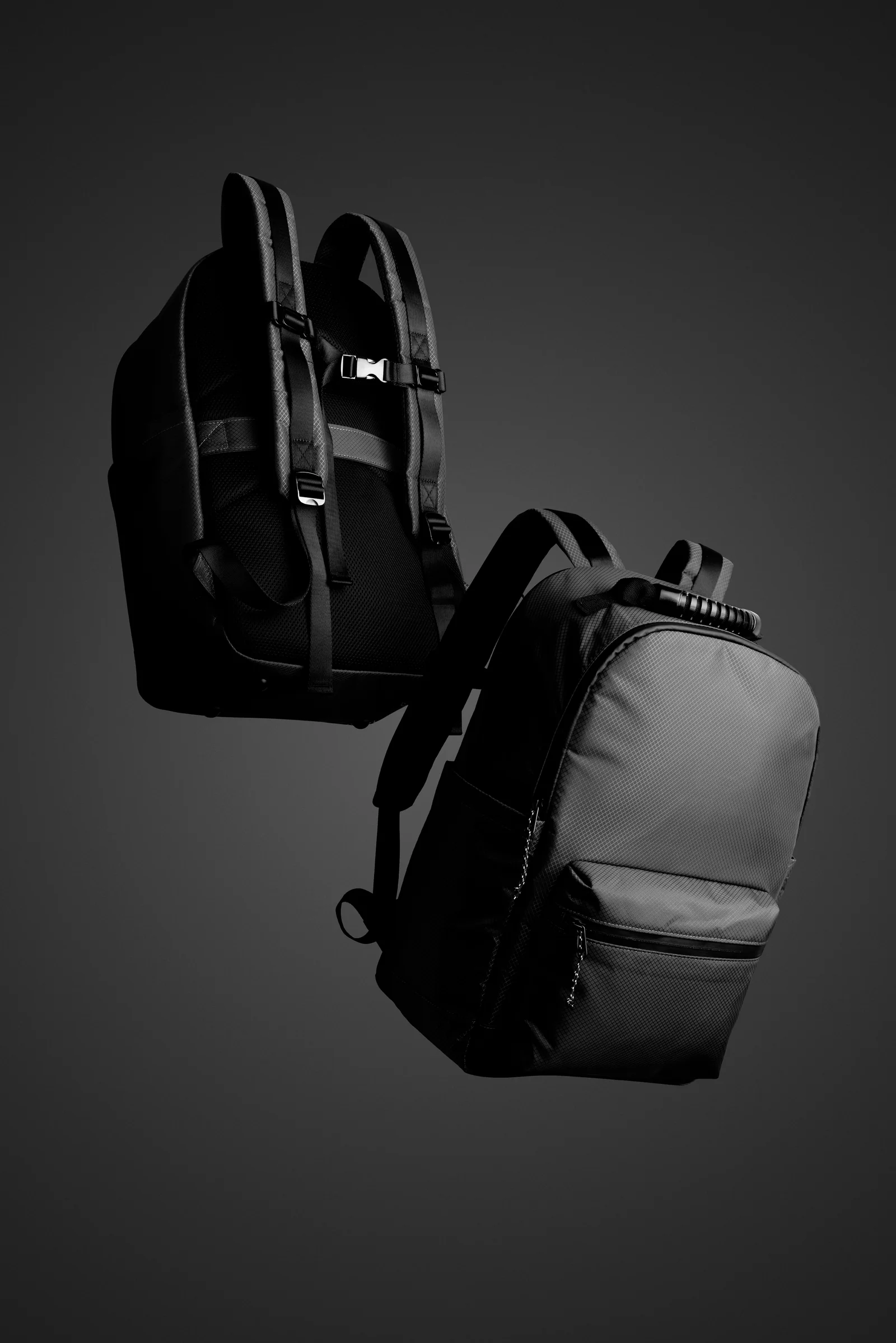 Front and rear views of a black Double Oak backpack suspended against dark grey.