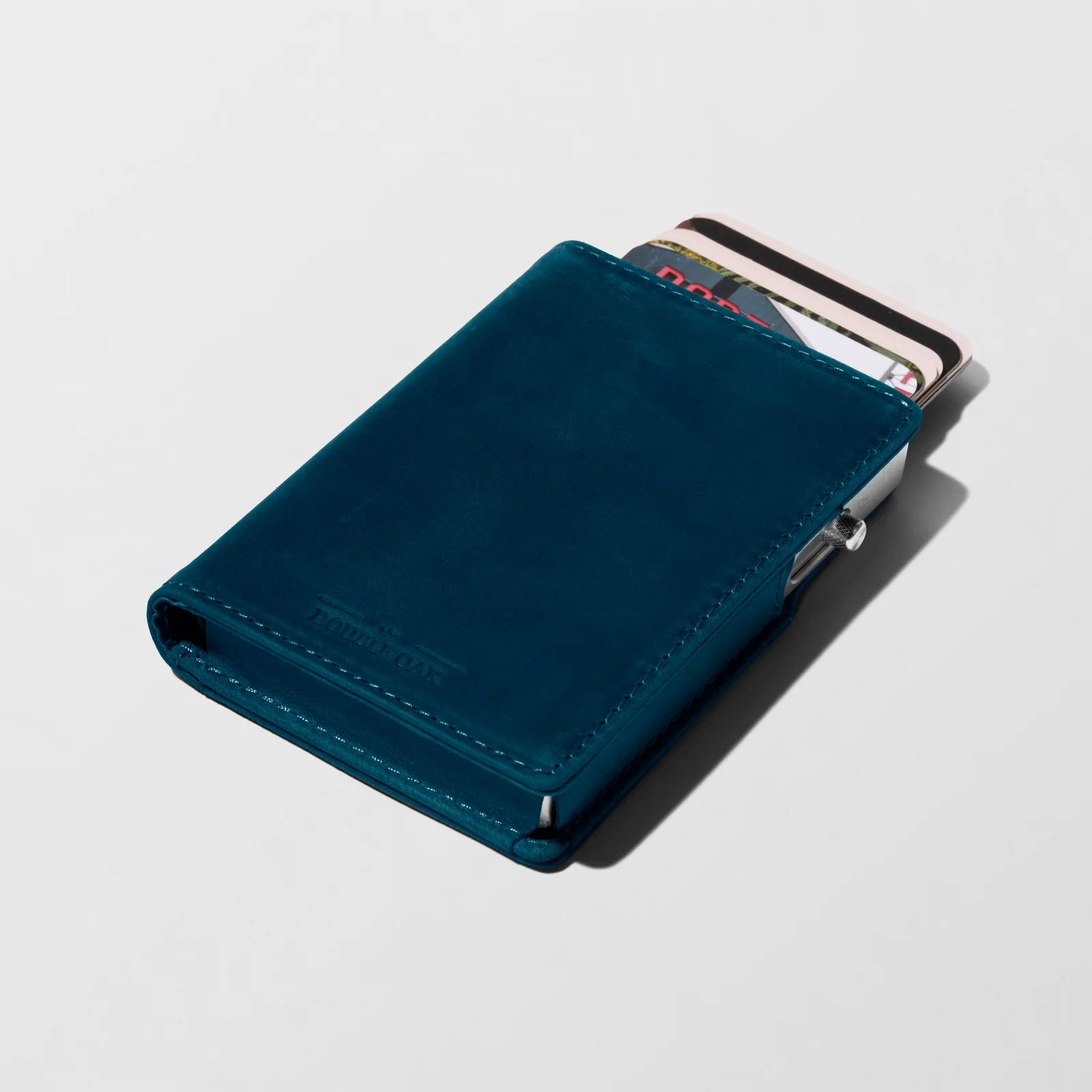 Blue Double Oak leather cardholder with cards protruding, photographed at an angle on a light background.