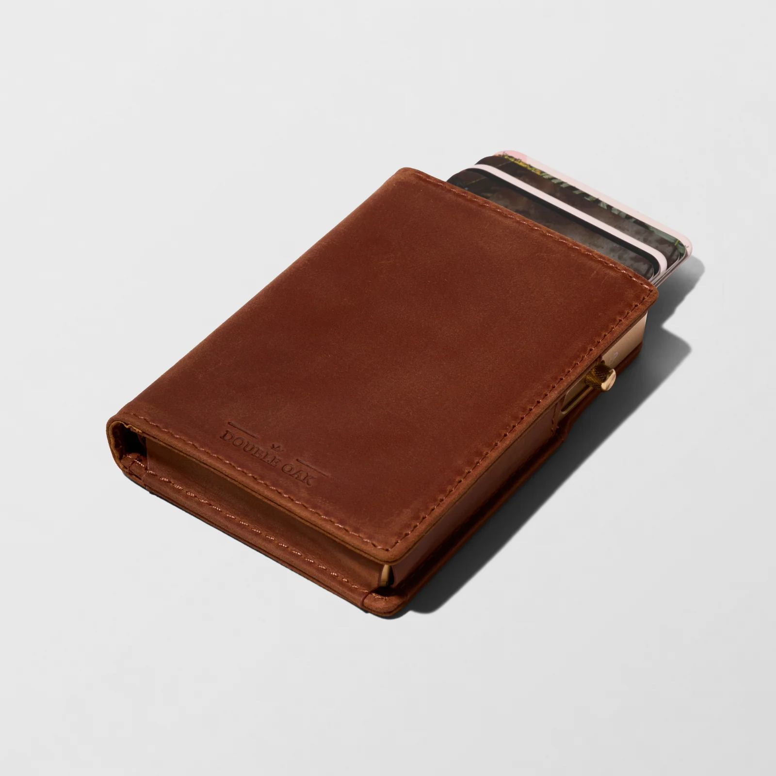 Brown Double Oak leather cardholder with cards protruding, photographed at an angle on a light background.