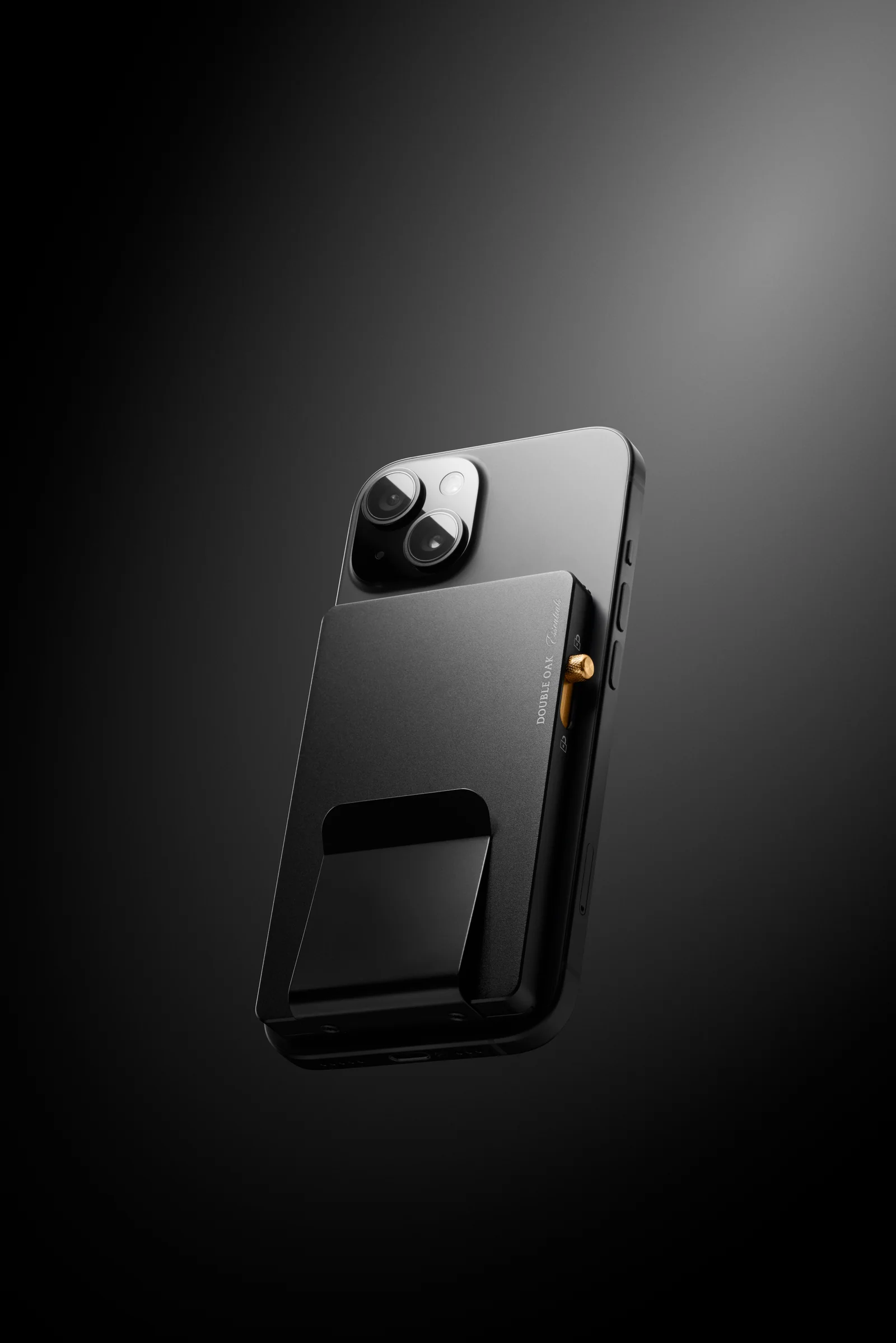 Black Double Oak cardholder attached to the back of a phone against a dark background.
