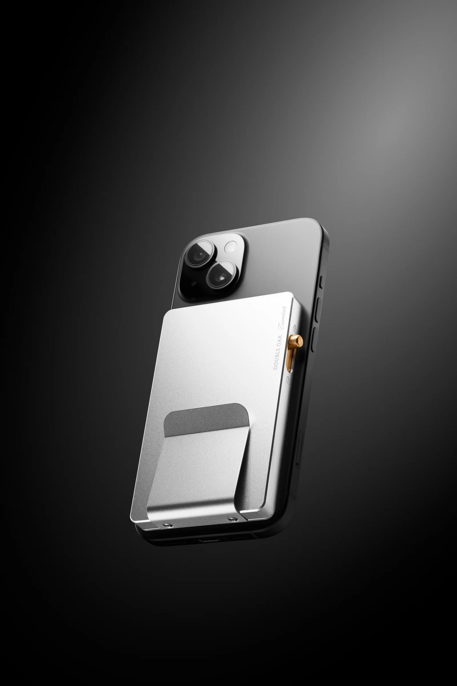 Silver-coloured Double Oak cardholder attached to the back of a phone against a dark background.