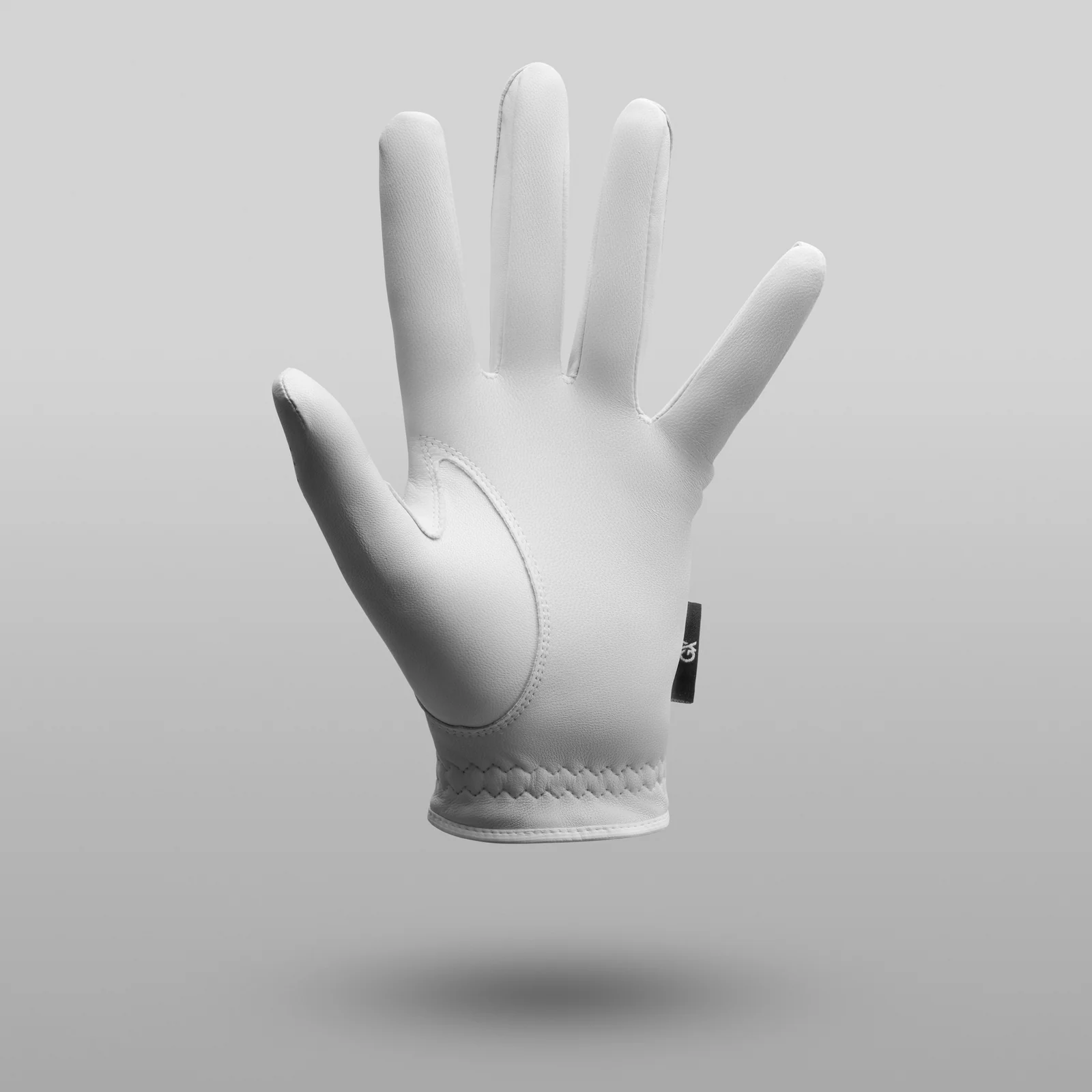 Palm view of a white GX Golf glove with stitched detailing above a soft shadow on grey.