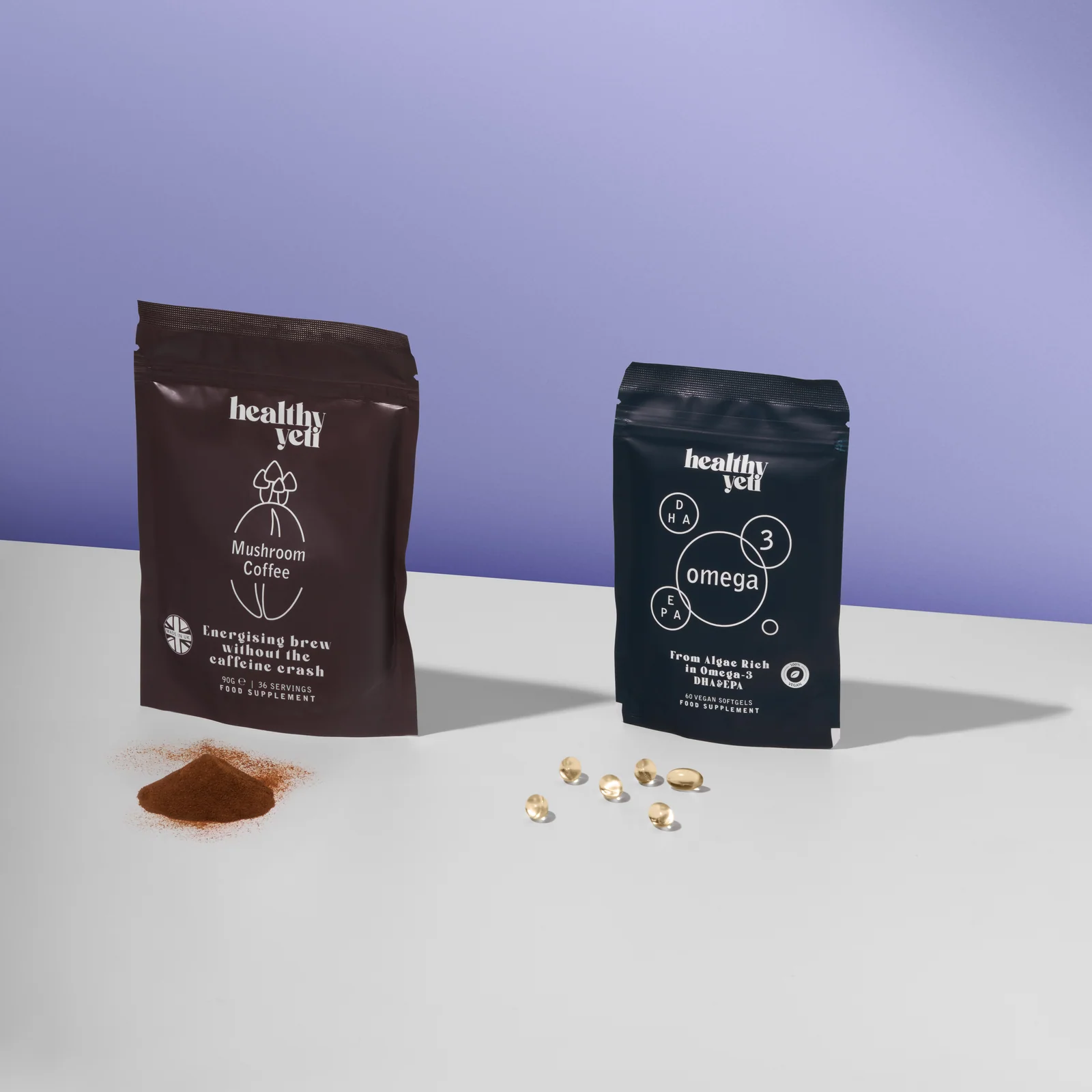 Healthy Yeti Mushroom Coffee and Omega 3 pouches with powder and capsules on a white surface against lilac.