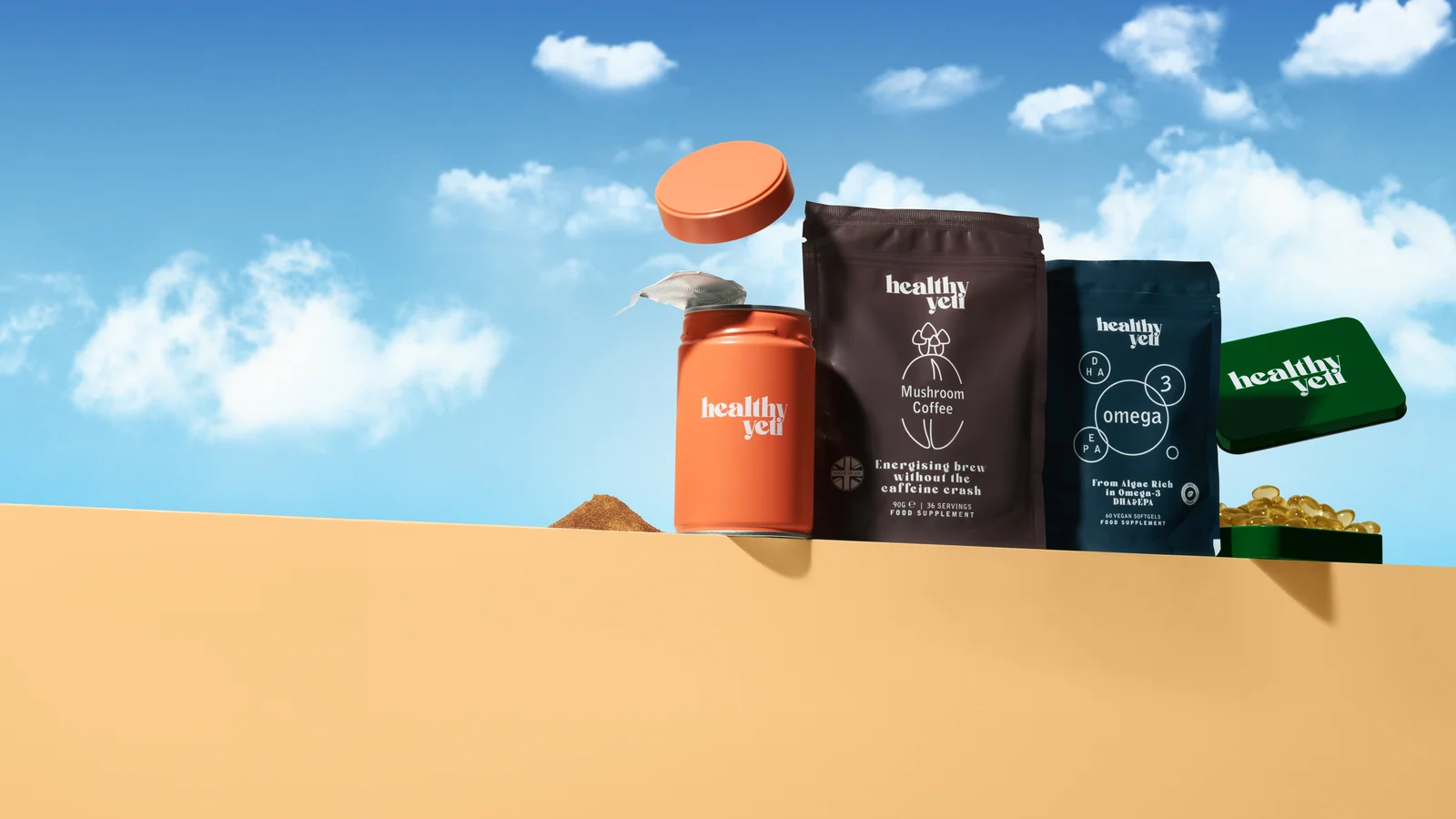 Healthy Yeti pouches, orange tin and green capsule tin on a yellow ledge beneath a blue sky.