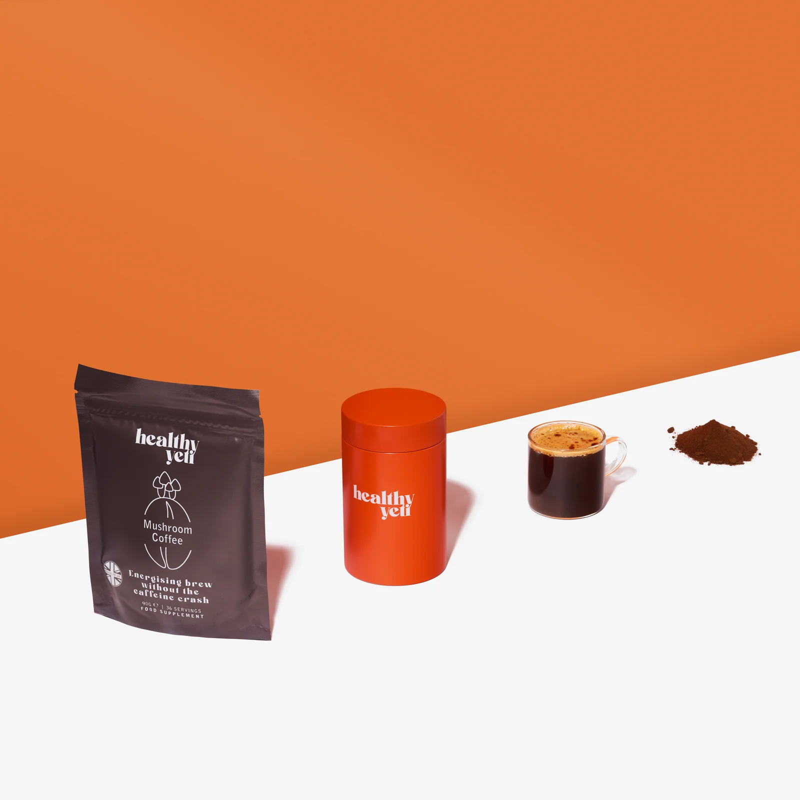 Overhead view of a Healthy Yeti Mushroom Coffee pouch, orange tin, cup and powder on white beneath an orange background.