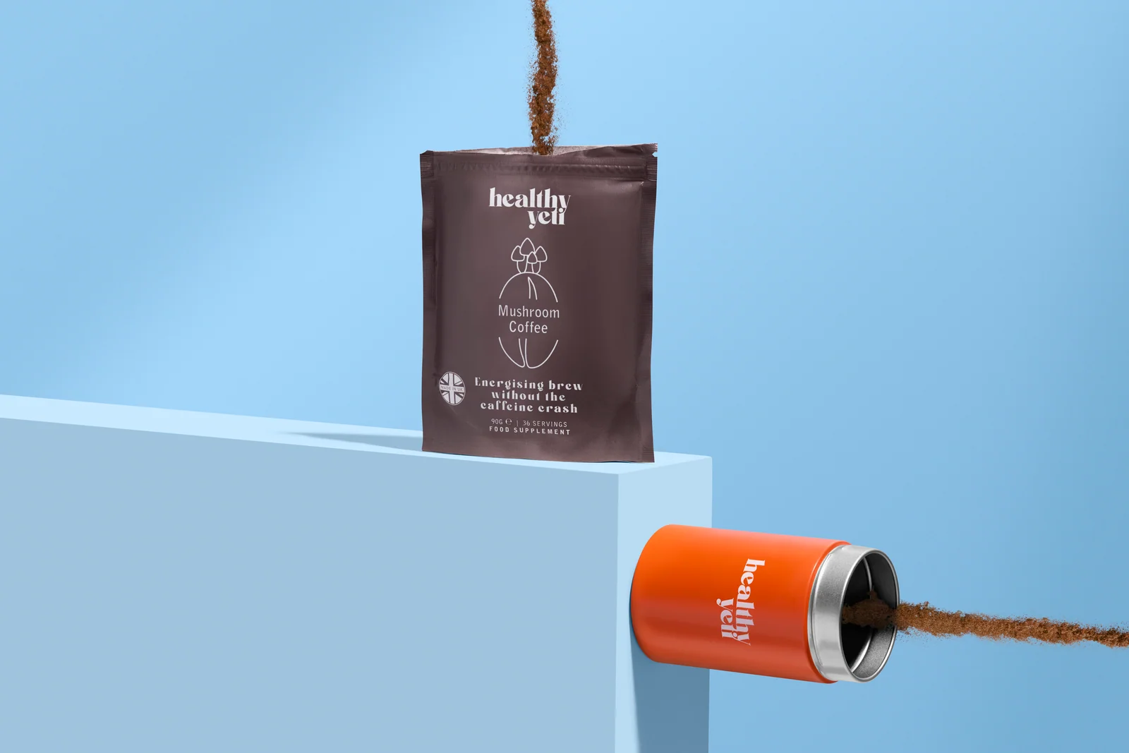 Healthy Yeti Mushroom Coffee pouch and orange tin with streams of coffee powder against blue.