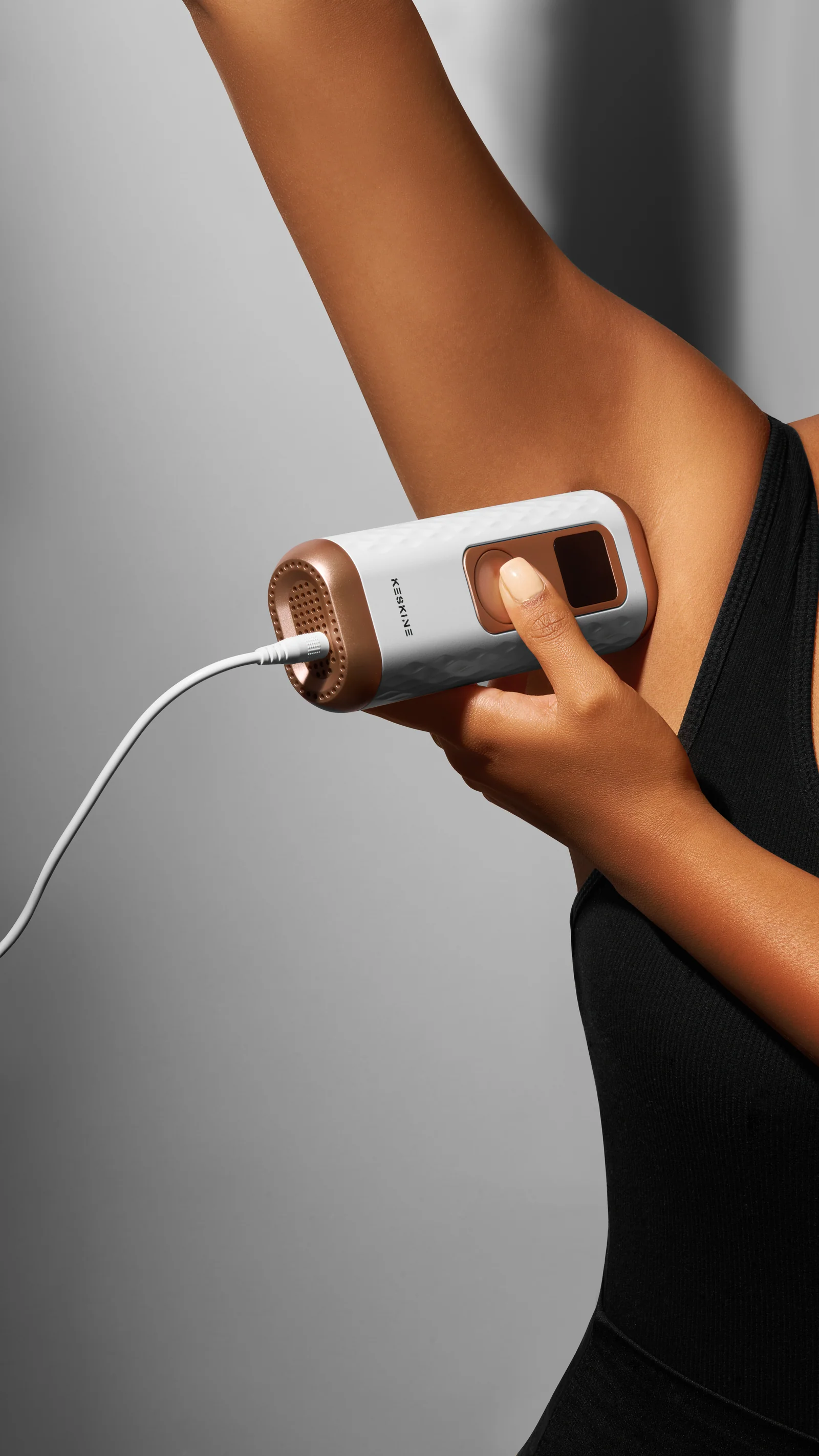 Person holding a Keskine IPL device against an underarm beneath a raised arm.