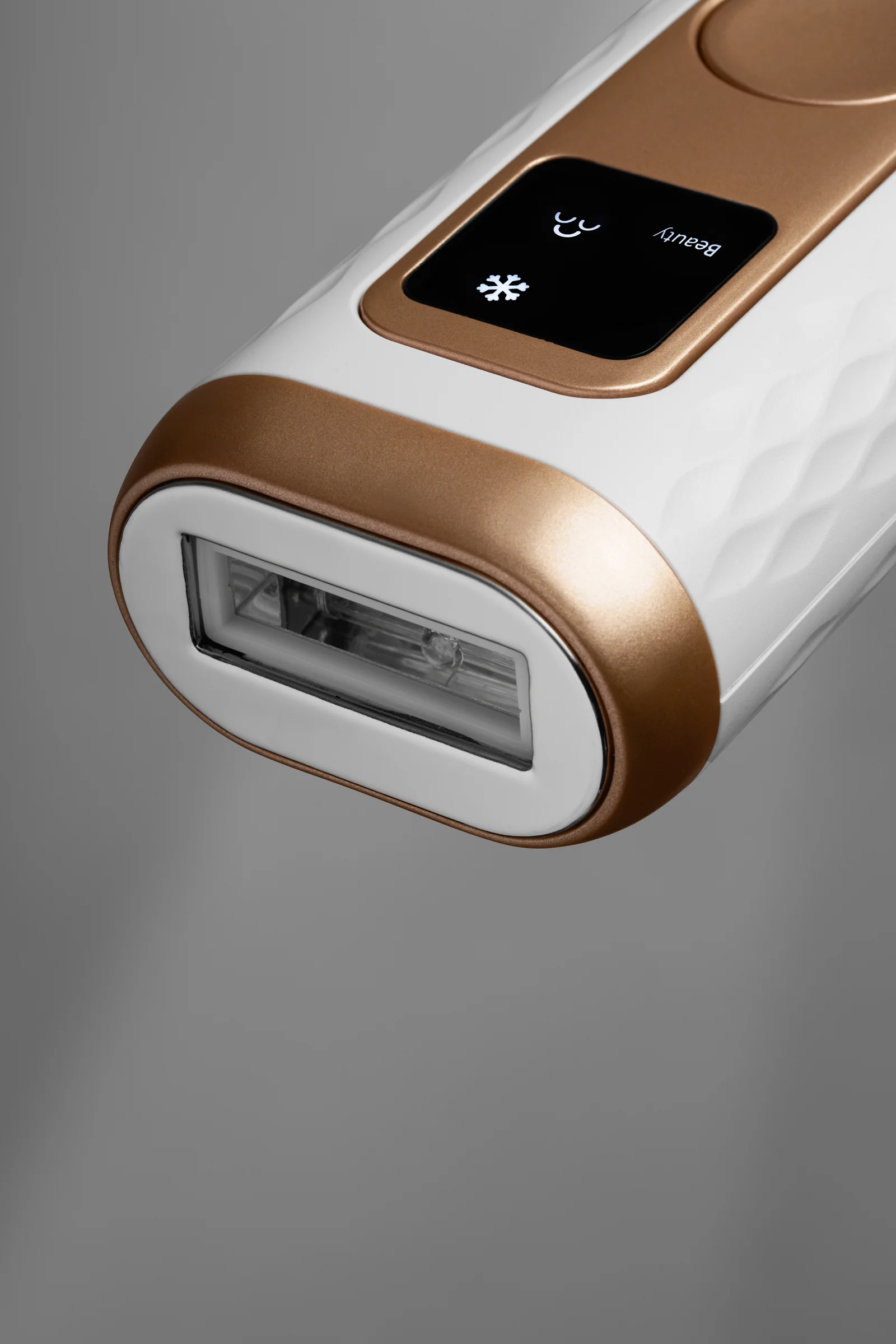 Close-up of the treatment window at the end of a white and gold Keskine IPL device.