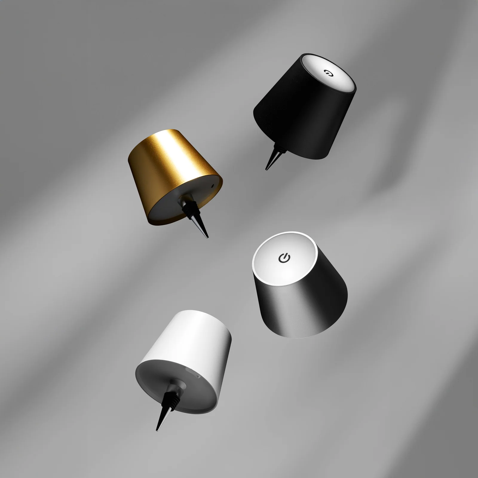 Gold, black, silver and white Liquor Lit lamp tops suspended at different angles against grey.