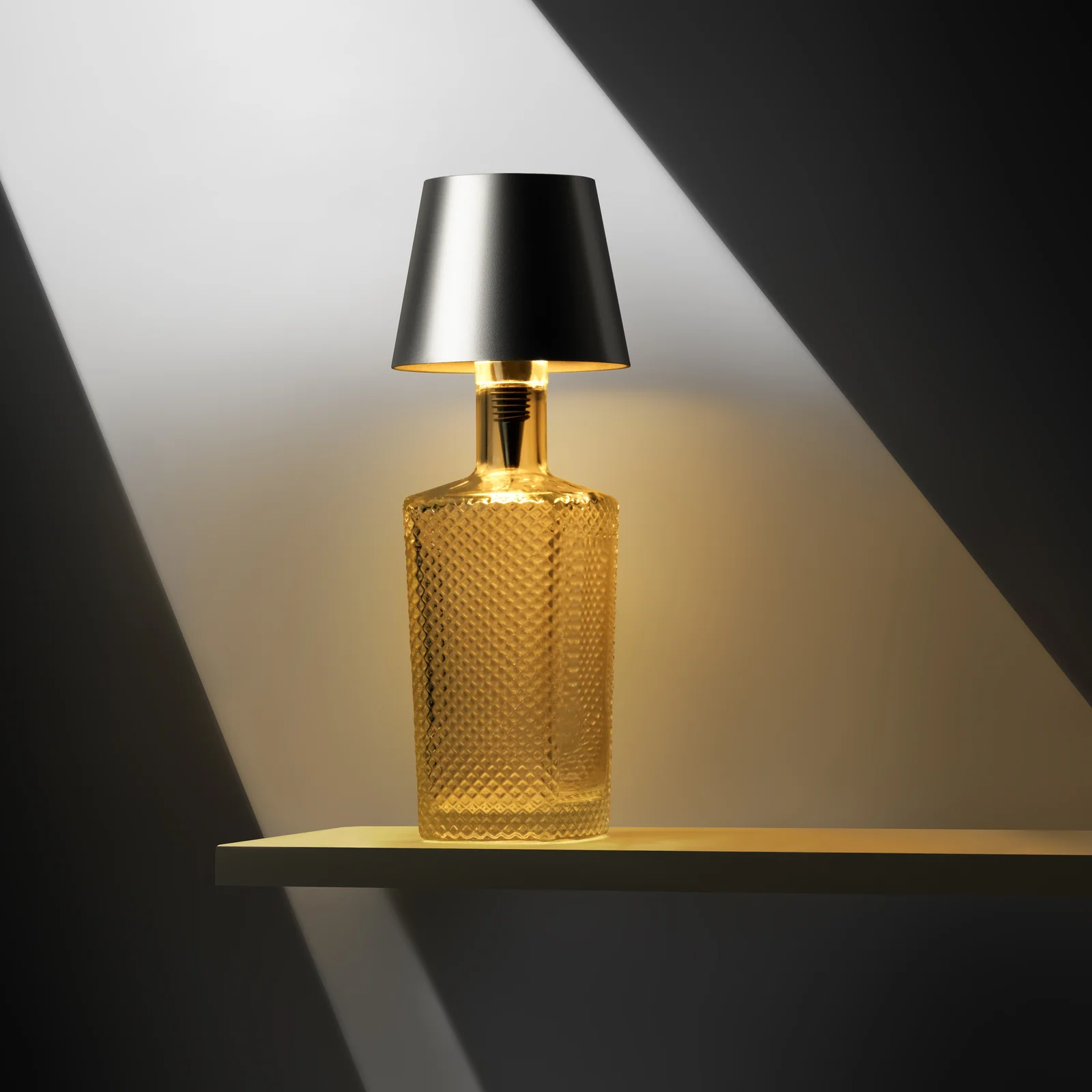 Glowing bottle lamp with a silver Liquor Lit top beneath a diagonal beam of light.