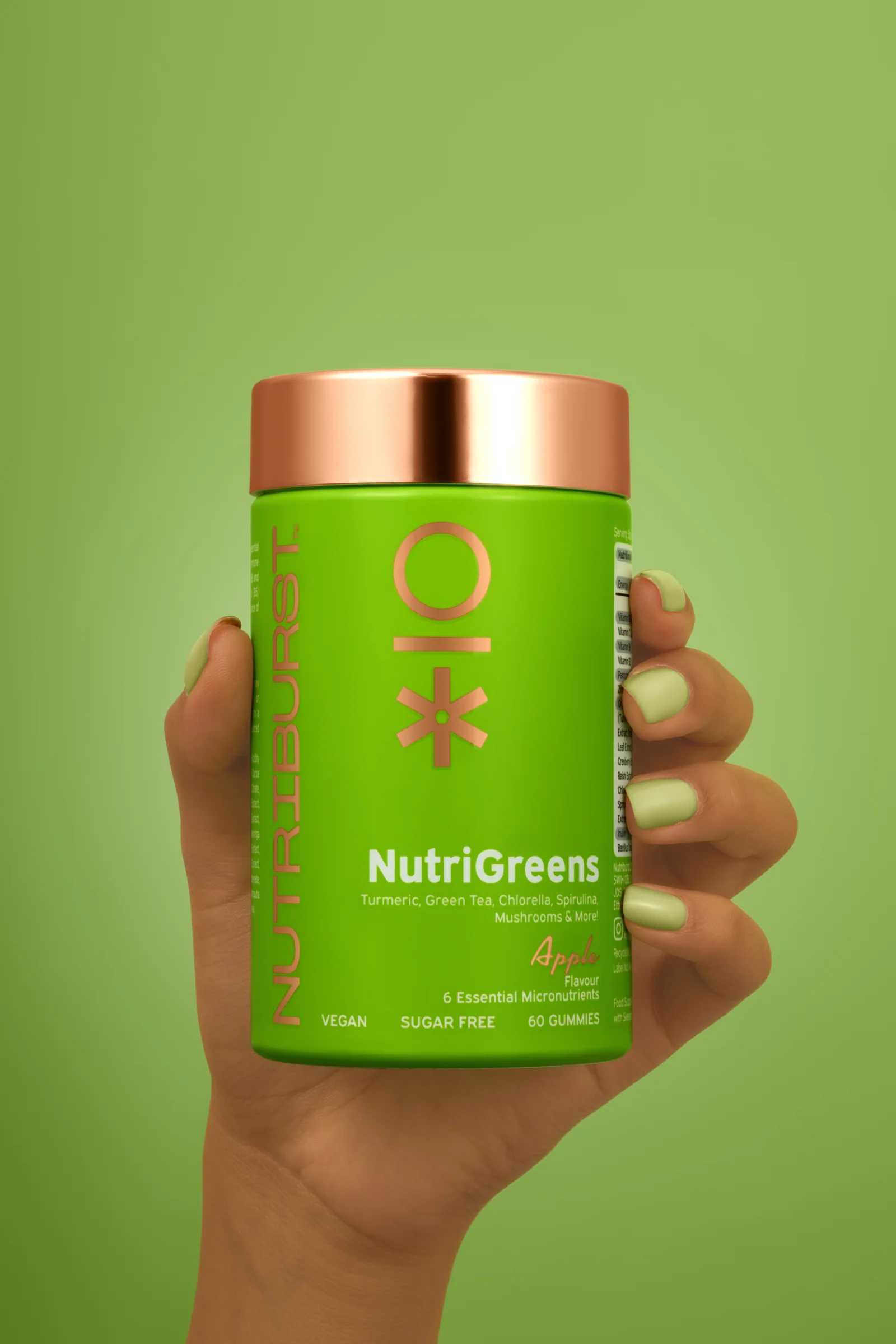 Hand holding a lime-green Nutriburst NutriGreens jar against a matching green background.