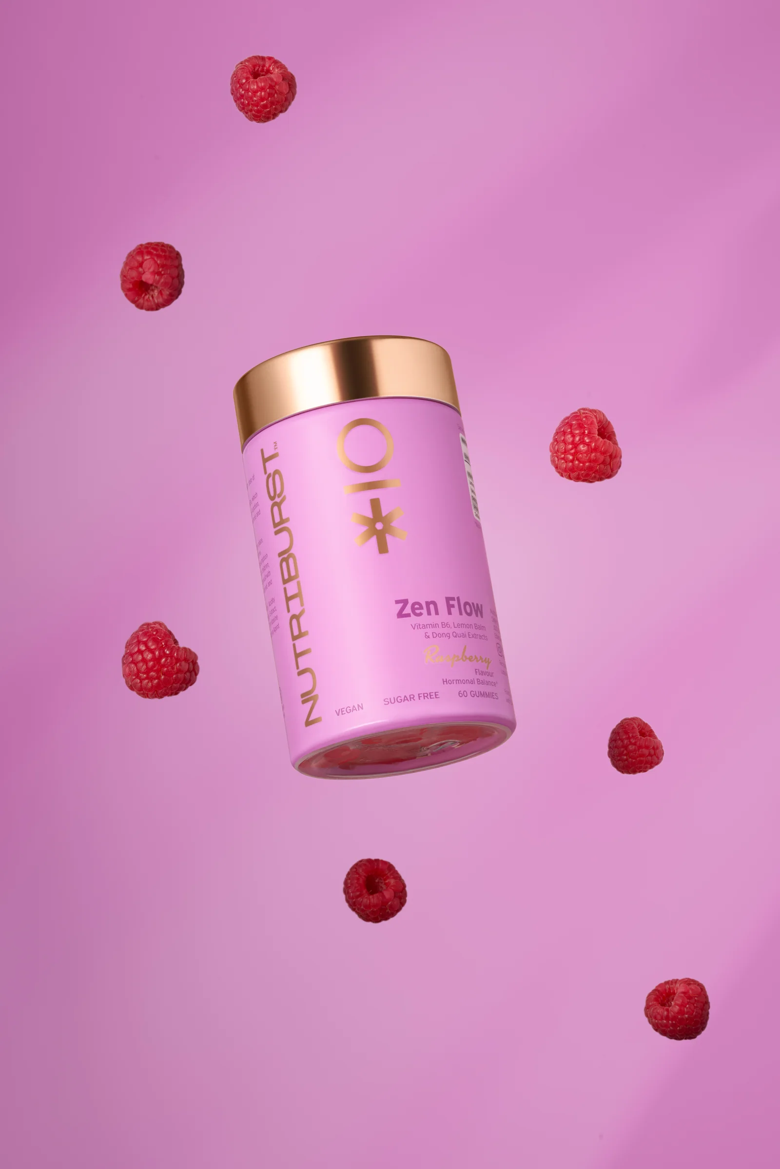 Pink Nutriburst Zen Flow jar surrounded by floating raspberries against pink.