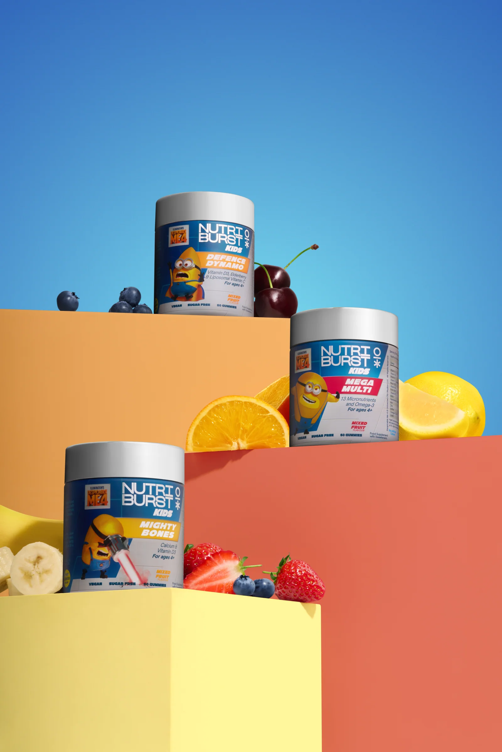 Nutriburst Minions jars with fruit on yellow, orange and red stepped platforms against blue.