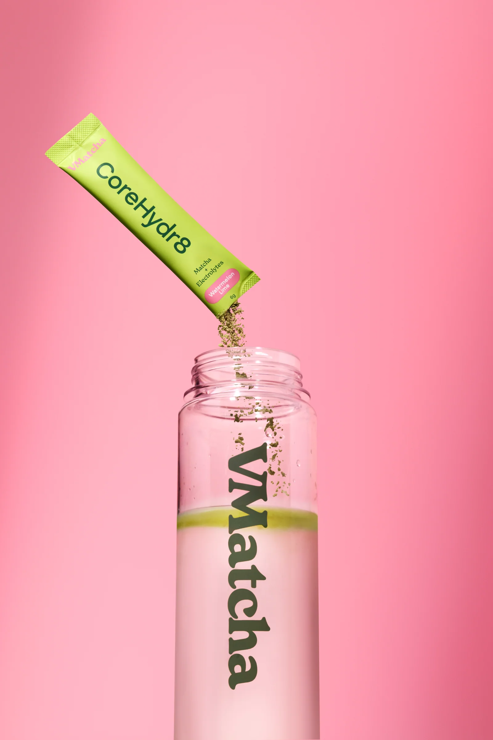 VMatcha CoreHydr8 sachet pouring powder into a branded bottle against pink.