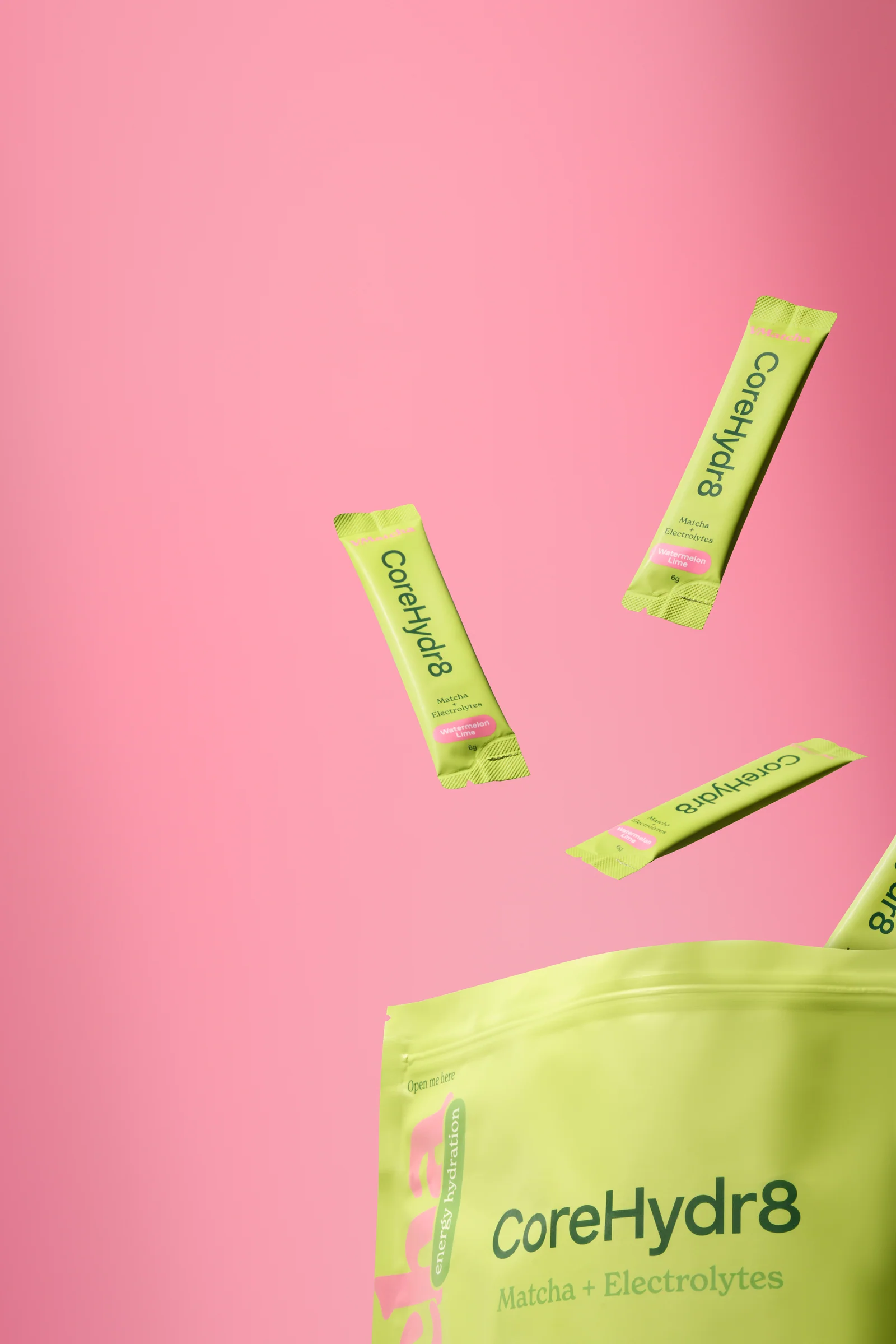 Lime-green VMatcha CoreHydr8 pouch with floating sachets against a pink background.
