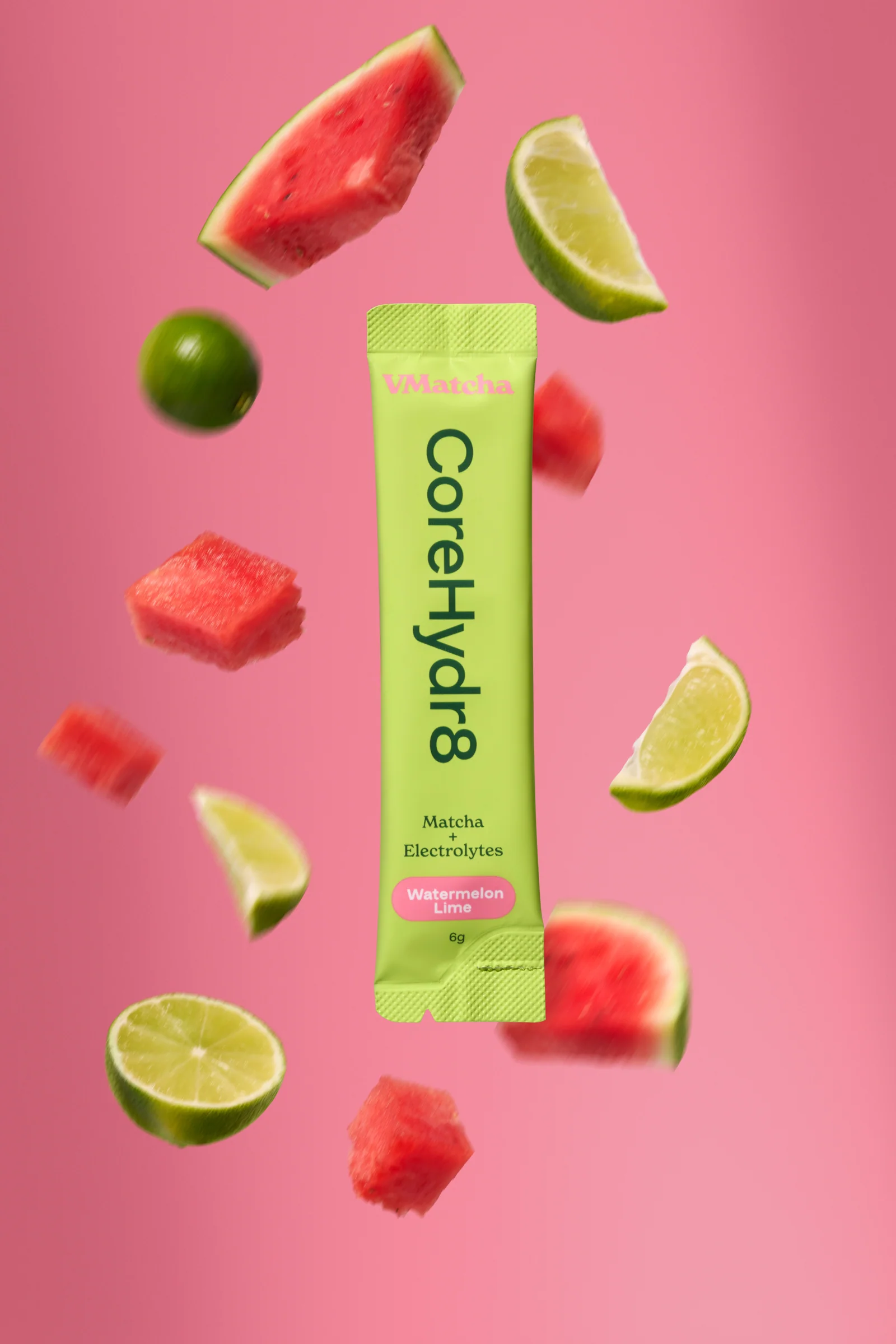 Green VMatcha CoreHydr8 sachet surrounded by watermelon pieces and lime wedges against pink.