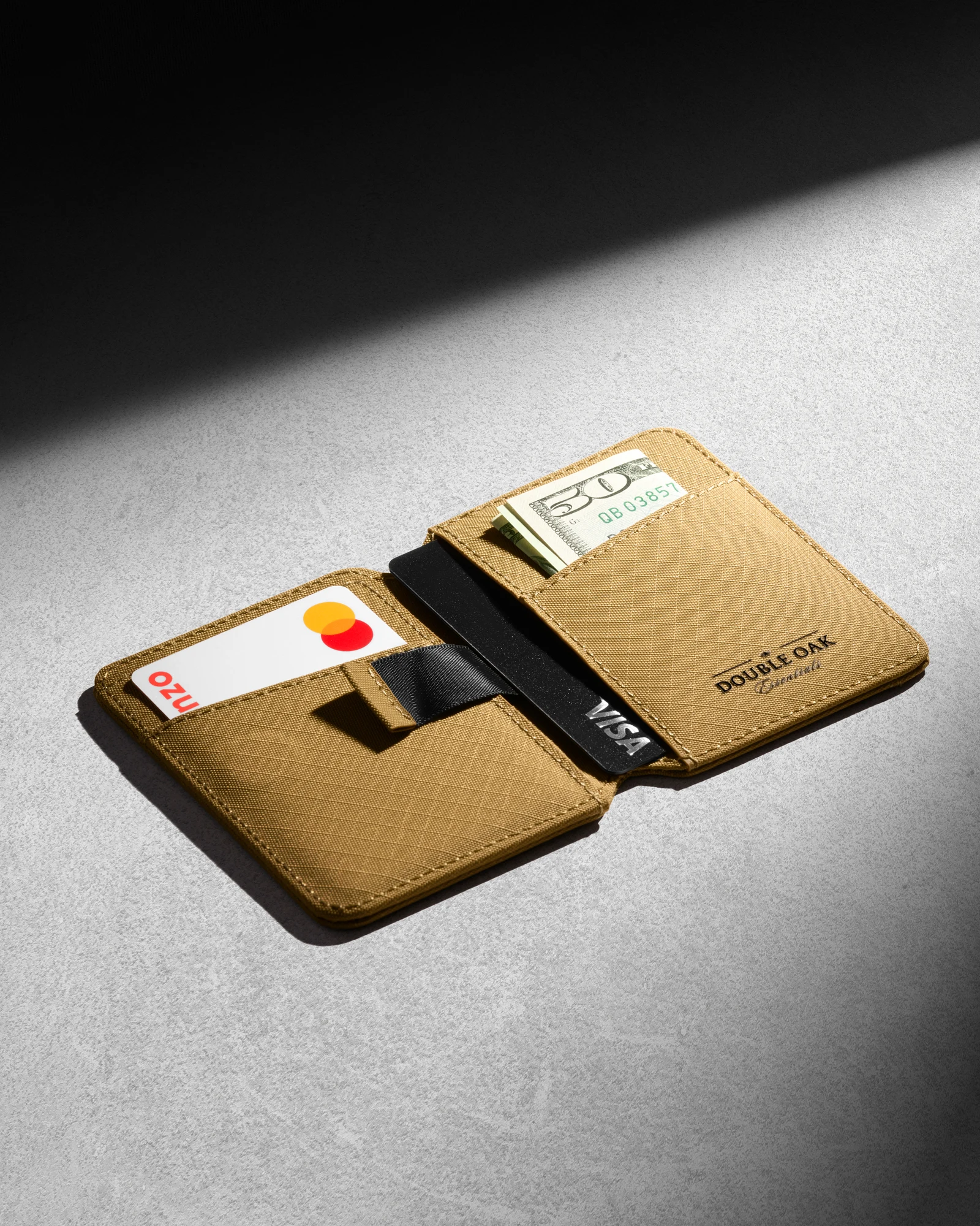 Open tan Double Oak wallet with cards on a grey surface in directional light.