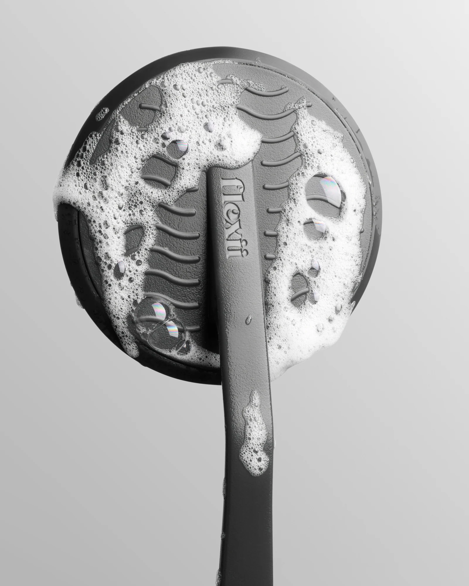 Grey Flexii brush with white foam, showing its textured surface.