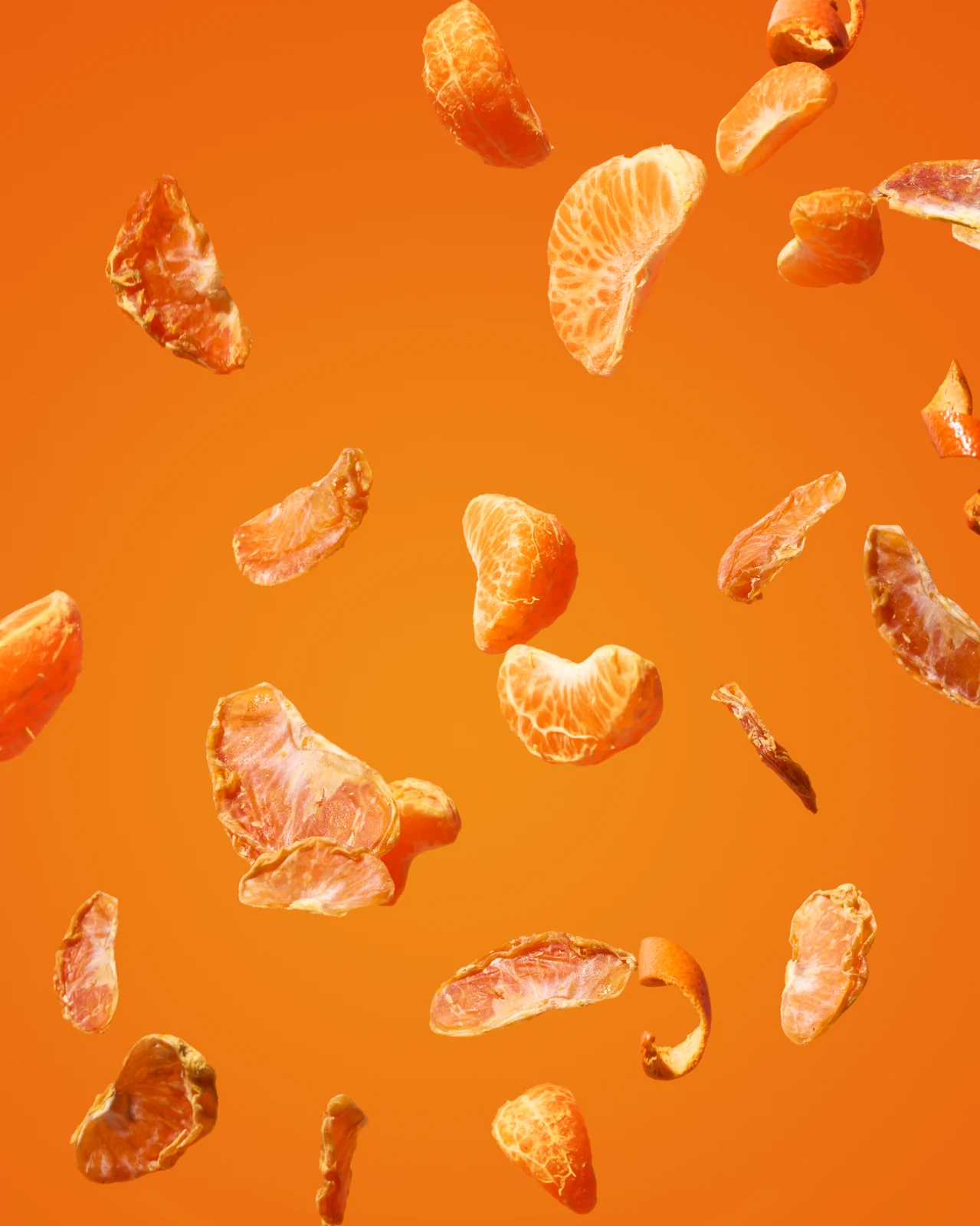 Fresh mandarin segments and dried slices suspended against an orange background.