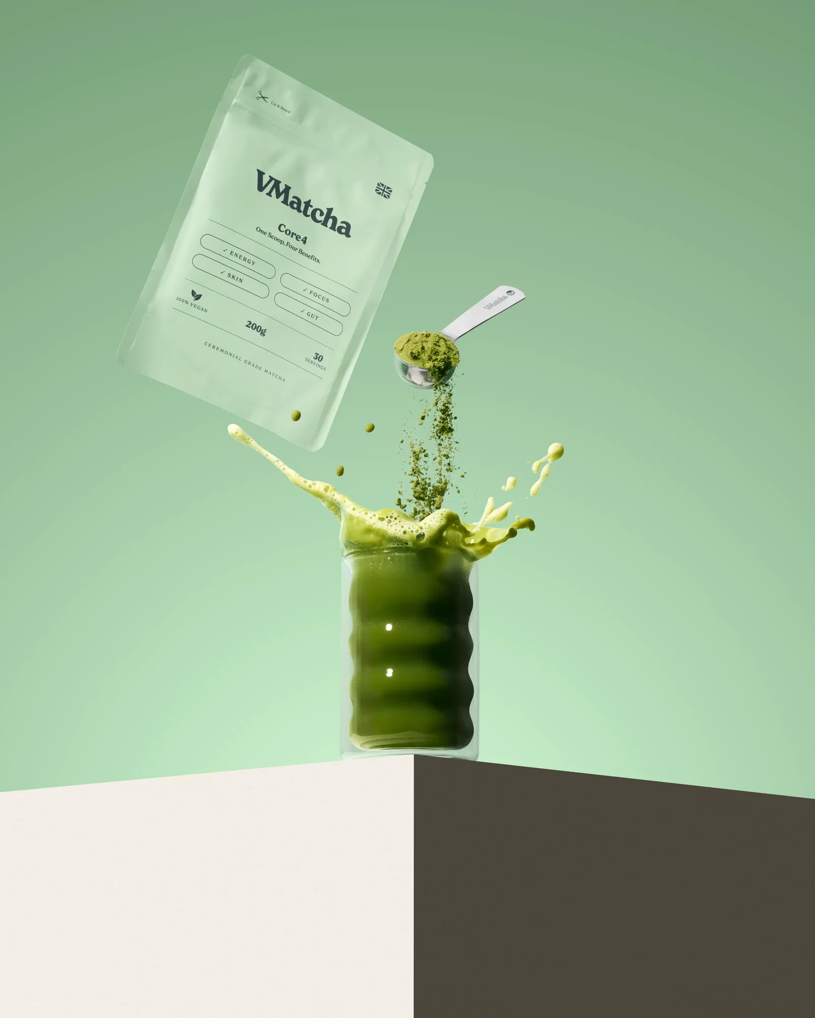 Suspended VMatcha pouch, spoon and matcha splash against mint green.