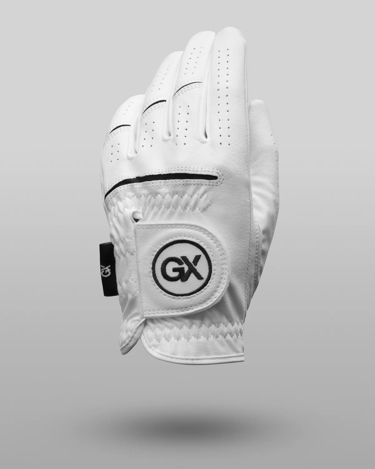White GX Golf glove suspended above a soft shadow on a grey background.